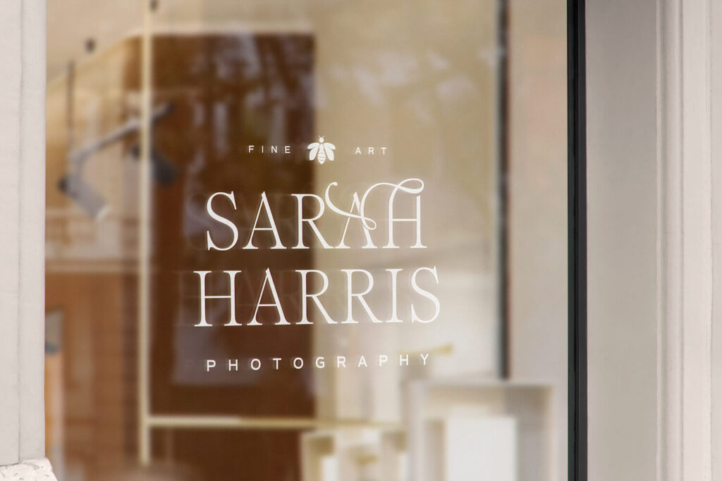 A mockup of the Sarah Harris Photography logo on a shop window, featuring the company name and their bee icon